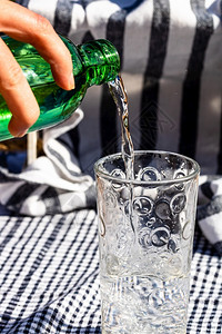 浇注将绿瓶水倒入玻璃杯健康气泡图片