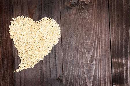 干燥照片中一由稻谷形成的心脏在木头背景的空地上形成食物粮图片