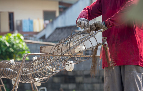 承包商男工人双手戴上套用铁丝绑住房屋或建筑结构的铁丝网板坯图片