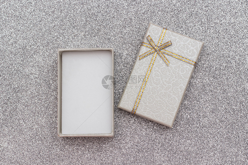 问候裹礼物打开灰色品盒打开灰色礼品盒在银光背景上用箭首打银闪亮的弓以最小样式显示复制空间模拟图片