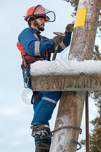 蓝色的腰带登山者冬季在电线杆上工作的蓝色电服气员背景