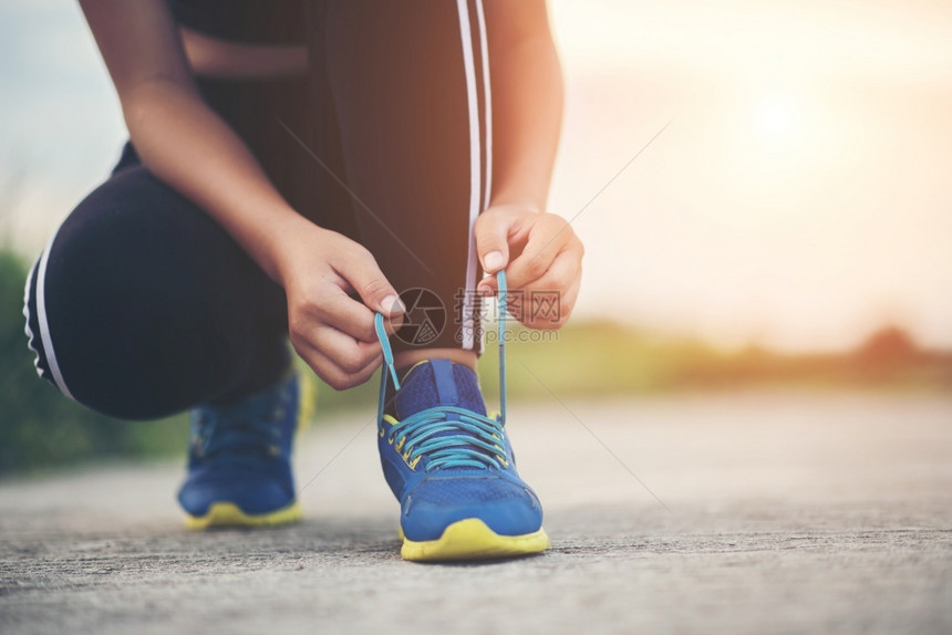 准备好外部女跑者绑着她的鞋去慢跑锻炼腿图片