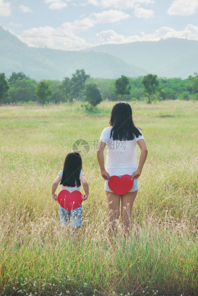 父母站在草地上背着红色的心抱一个红站立在草地上T恤母亲图片