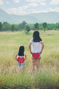 父母站在草地上背着红色的心抱一个红站立在草地上T恤母亲图片