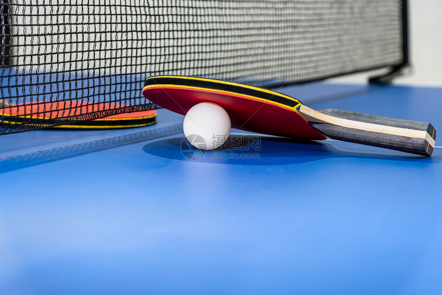 为了红桌网球拍和在蓝乒乓桌上用黑网的白球两桌板是体育竞赛设备用于室内活动以及概念背景运动红桌网球一个红桌俱乐部趣图片