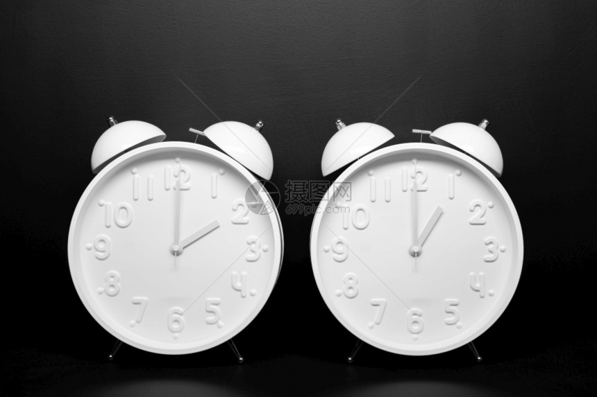 背部倒数日光节省时间概念2个白色反时钟在黑背景上孤立于黑色背景空间复制双胞胎图片