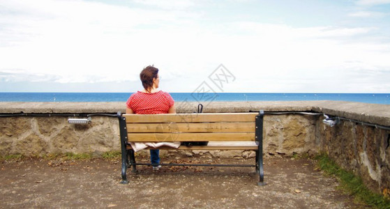 海滩一种孤单的女人坐在海边长椅上看着大海快乐的图片