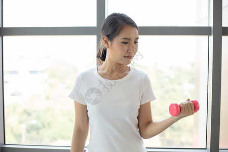 吸引人的拉伸亚裔妇女在家里用哑铃做运动力量图片