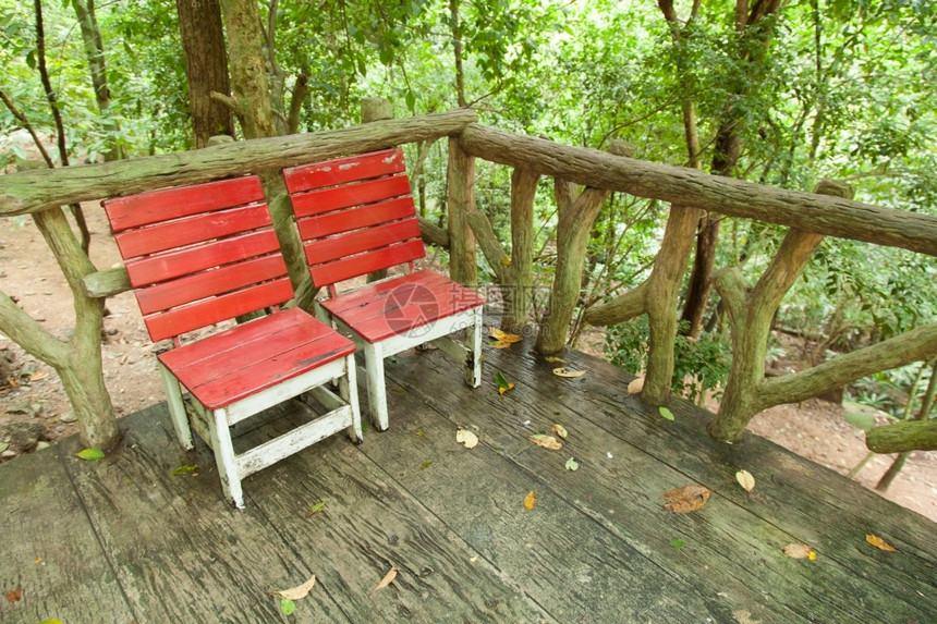 在下面木头红椅子2位于花园树下木甲板上在花园的树下绿色图片