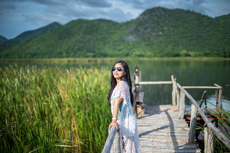 年轻女站在木桥上以自然背景为本蓝色的早晨热带图片