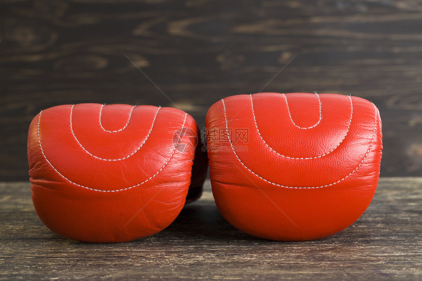 说谎单身的一对红色拳击手套躺在黑木板上涂有油漆的运动用品戴上一双红拳击手套昏死图片