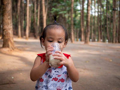 亚洲小孩在花园里喝杯子牛奶食物健康概念很好吃笑声可爱的饮食早餐图片