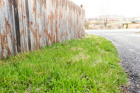 木板树制的在农村旧板草坪有围栏的土地上木栅栏下的绿草图片