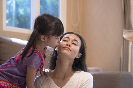 接吻选择地关注小亚洲女孩在家里客厅亲妈的脸颊以亲吻母的脸颊孩子窗户图片