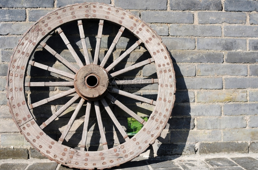手工制作的传统古老车轮对着砖墙图片