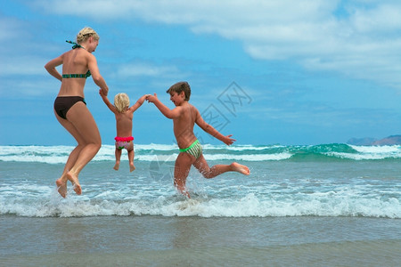 母亲和两个孩子在海滩上玩耍图片