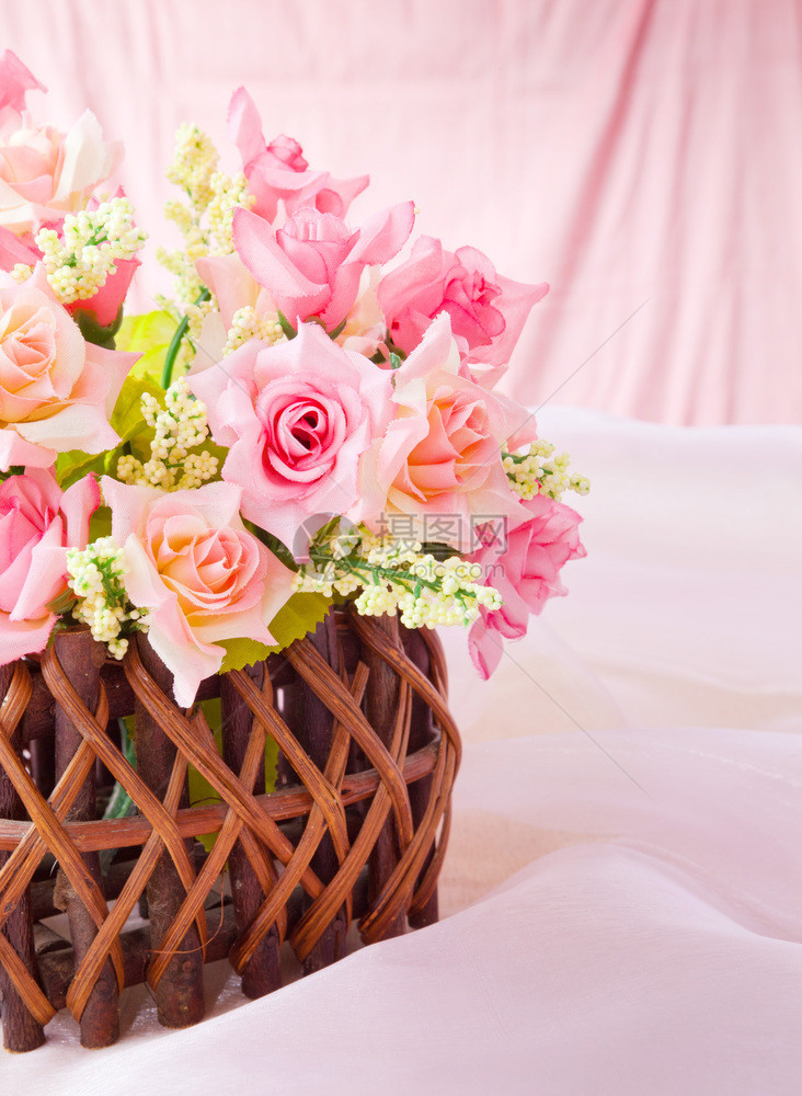 优雅束粉红背景的织物木篮子中玫瑰图片