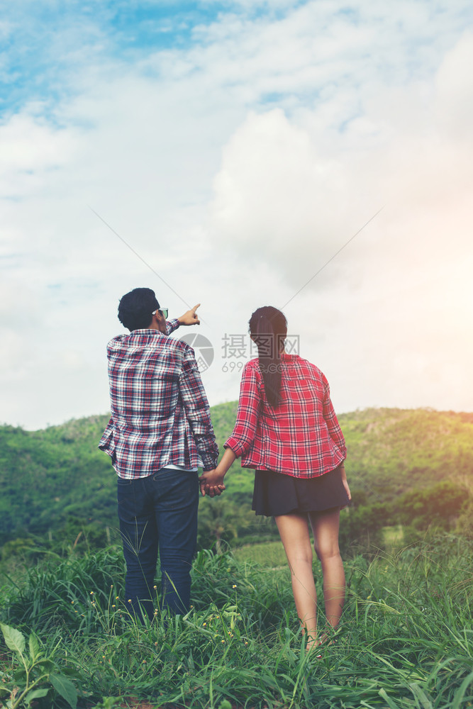 潮人男年轻的嬉皮士夫妇手牵在草地上散步成人图片