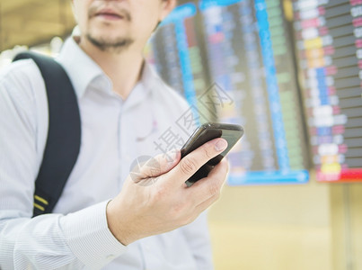 在机场终点站旅行时使用移动电话的商务旅行者游客时间表信息男人图片