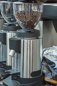 带棕色咖啡豆的银电动咖啡研磨机带豆的银色电动咖啡研磨机新鲜的黑暗食物图片