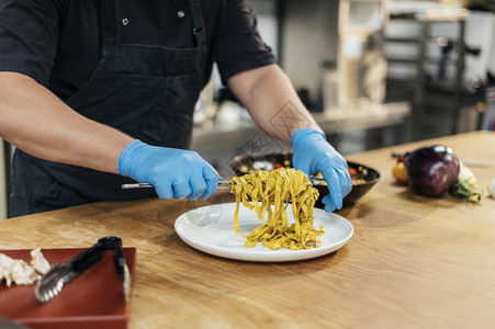 男厨师戴手套把意大利面盘帕尔马干酪厨房准备图片