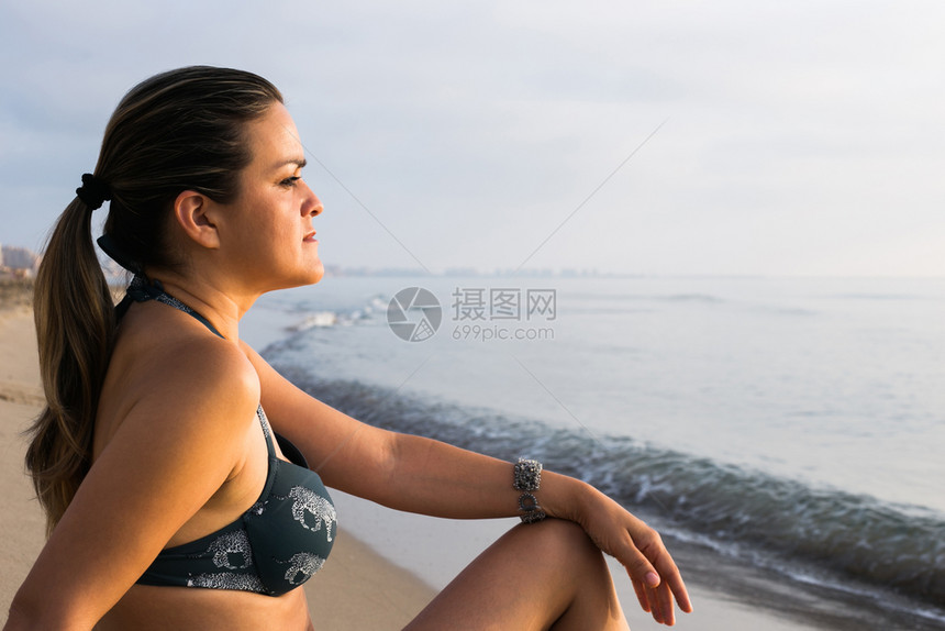 放松女人在沙海滩上享受日出异国情调脸图片