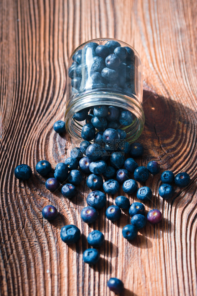 成熟最佳将新收集的蓝莓放入罐子中一些水果自由散布在旧木制桌子上健康图片