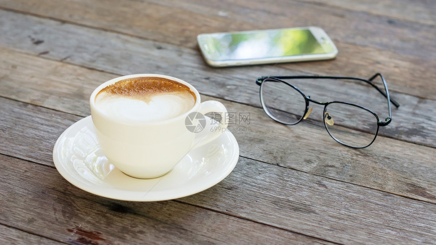 热咖啡眼镜和木制桌上的智能手机热香气杯子图片