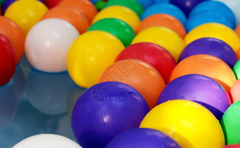 彩色晶格化喜悦儿童游泳池中蓝水背景的彩色球在儿童游泳池中可塑化彩色球的背景上目孩子们背景
