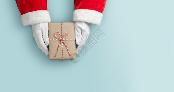 诺克萨斯之手问候圣诞快乐概念达克萨斯之手的顶端视野拿着一个棕色礼物盒或现装子在蓝色孤立的背景上横幅圣诞节背景