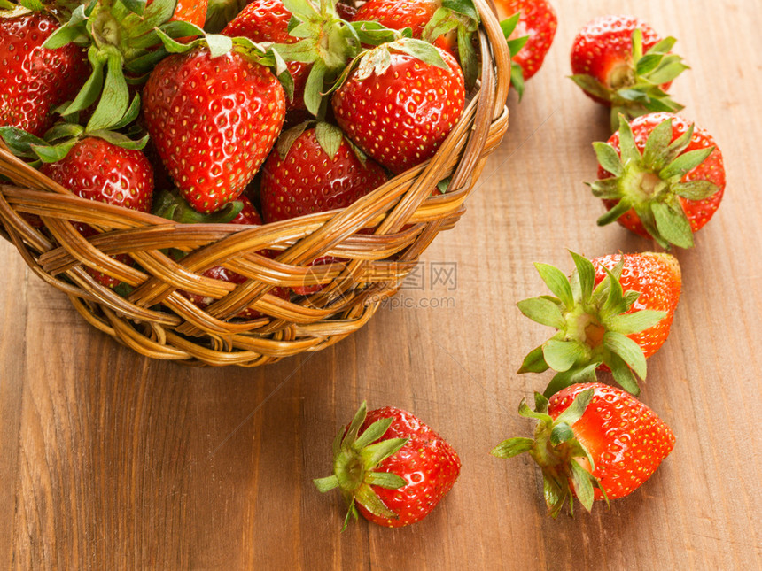 一篮子中的红草莓放在木制桌板上的篮子中上还有新鲜的红草莓在木制桌子上夏天自然水果图片