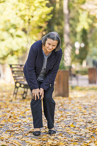 补救老年女子在秋天公园散步膝痛患有关节炎疼痛概念步行风湿病图片