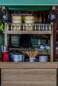 前面放着筷子复古的在餐厅前面展示观古风店口调Wooden柜台配有平托陶瓷碗木棍不锈钢锅反光铝花瓶和煤气灯经典的文化背景