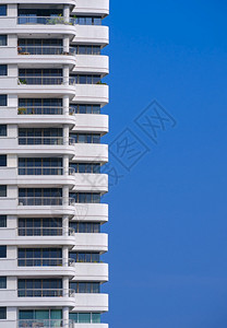 蓝色的玻璃垂直框中蓝色清晰天空背景的高住宅楼公交器以显示垂直框架中的蓝亮天空背景清除图片