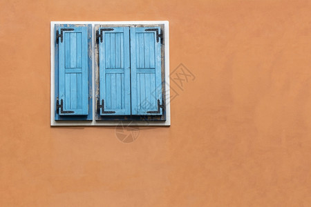 框架橙色外墙上的蓝木窗百叶建造优质的图片
