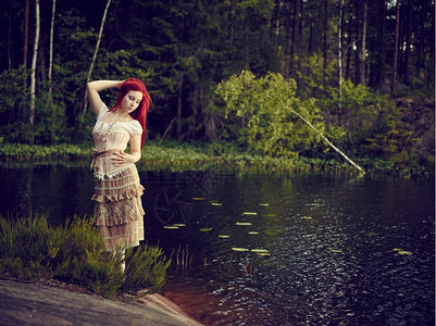 森林独自的穿着裙子迷人年轻女站在水线边背面湖身着洋装迷人的图片