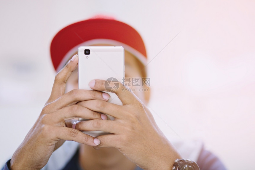 穿着红色帽子的男用手机打智能电话玩手或成人聪明的图片