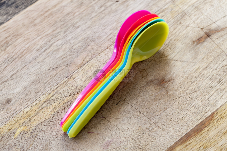 几个多色可支配塑料勺子用黑色厨房的有勺子合在一起放桌子上厨房的有色勺子中紧闭盘目的干净图片