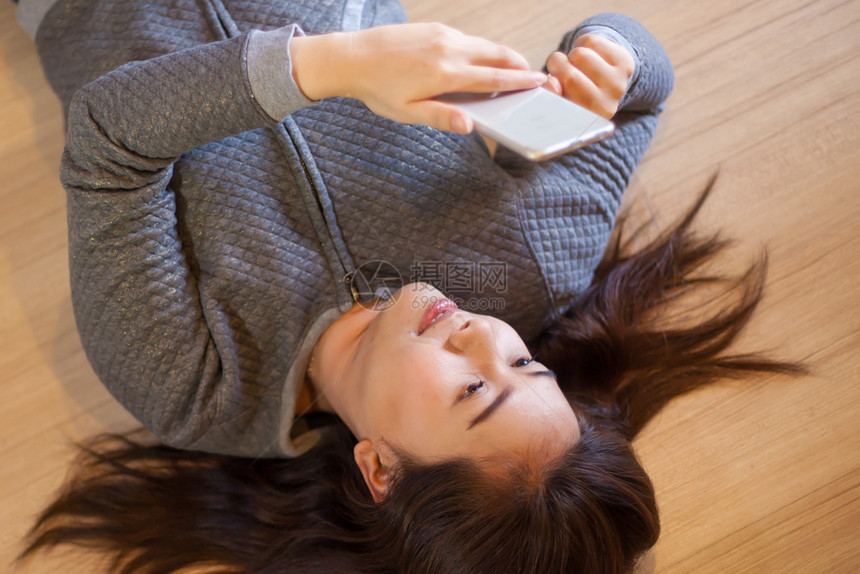 技术在家里使用智能电话说谎的快乐亚洲年轻女幸福随意的图片