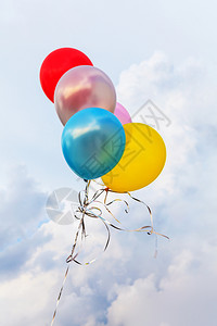 庆祝蓝色天空背景上的多彩气球五纸屑惊喜图片