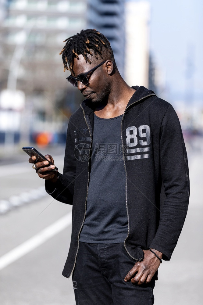 城市的闲暇常设黑人男在户外使用手机戴太阳眼镜图片