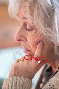 用绳子绑在手指上作为提醒的高级妇女特写八十年代困惑退休图片