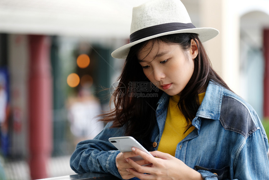 年轻亚洲女在市外咖啡馆前使用电话的年轻女他们以户外技术生活方式为背景在户外工作的人亚洲商业们图片