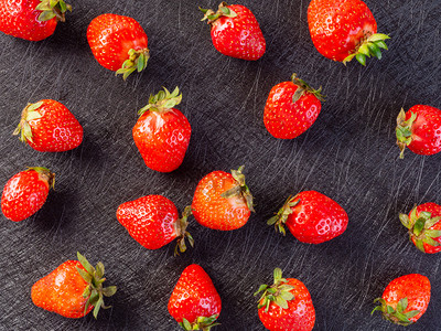 黑色背景上的草莓图案黑色背景上的新鲜草莓图案夏天甜点食物背景图片