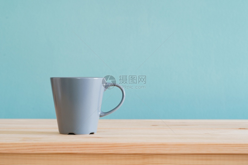 茶产品棕色木头桌上的咖啡杯和蓝色壁纸上带复制空间的布质背景休息图片