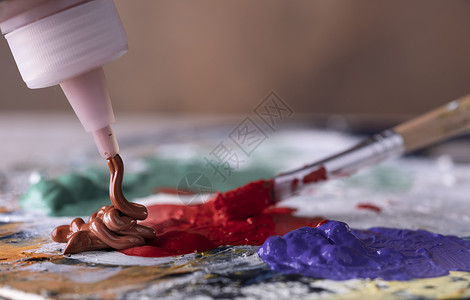 女创意艺术家使用油漆刷在彩色调盘上混合绿和红油涂料明亮的作坊图片