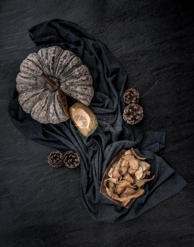 可口黑色的烹饪石纹理上自制的香脆南瓜芯片和美味极了的平板布料图片