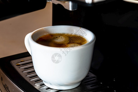 最佳早餐杯子装满咖啡机时一杯浓缩咖啡拿铁图片