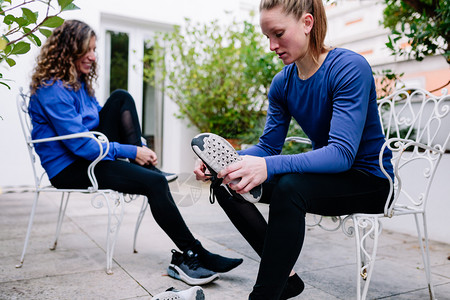 锻炼两名年轻女运动员在训练前系鞋带绑上她的然后在露台穿运动衫移减肥图片