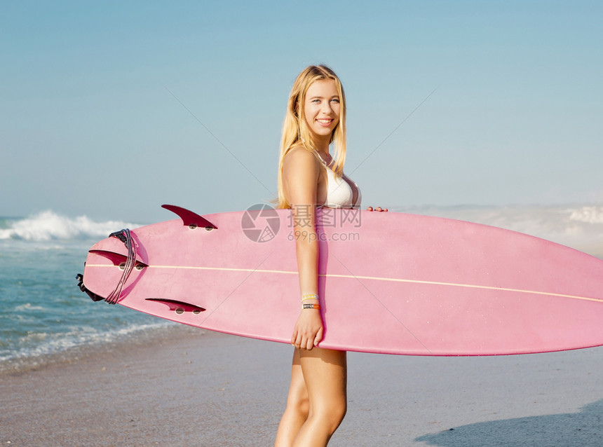 海滩上冲浪女孩带着她的冲浪板图片